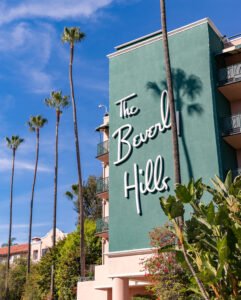 Beverly Hills in Los Angeles United States - November 17 2022 A picture of The Beverly Hills Hotels sign on its facade and the nearby palm trees - Kay And Associates The Beverly Hills Hotel building in Beverly Hills, California, with palm trees growing beside it.